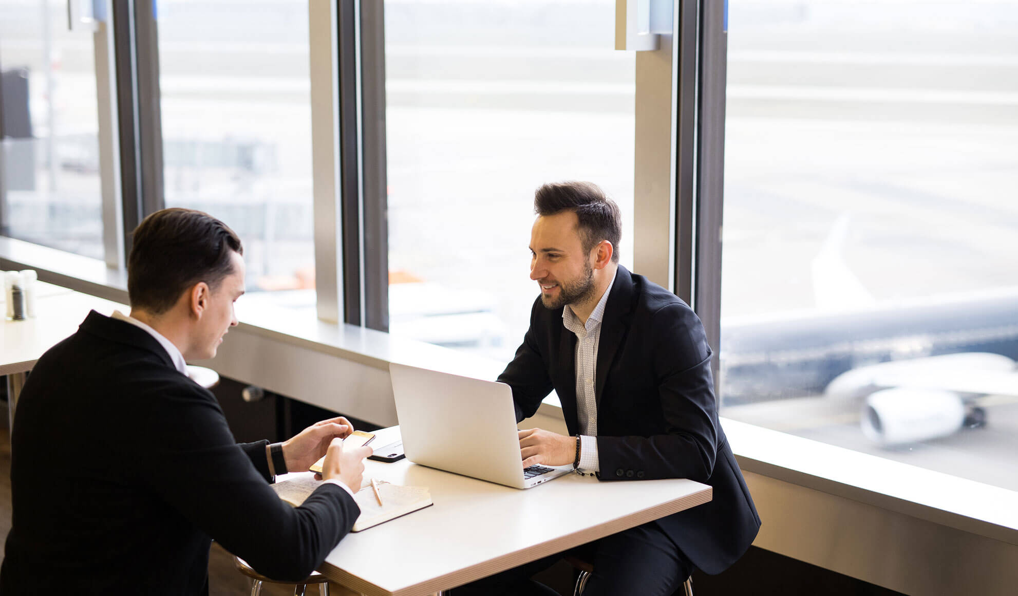 flyness consulenza air charter broker Consulente air charter broker con cliente in una business lounge, mentre analizzano opzioni per charter personalizzato. Flyness, air chartering.