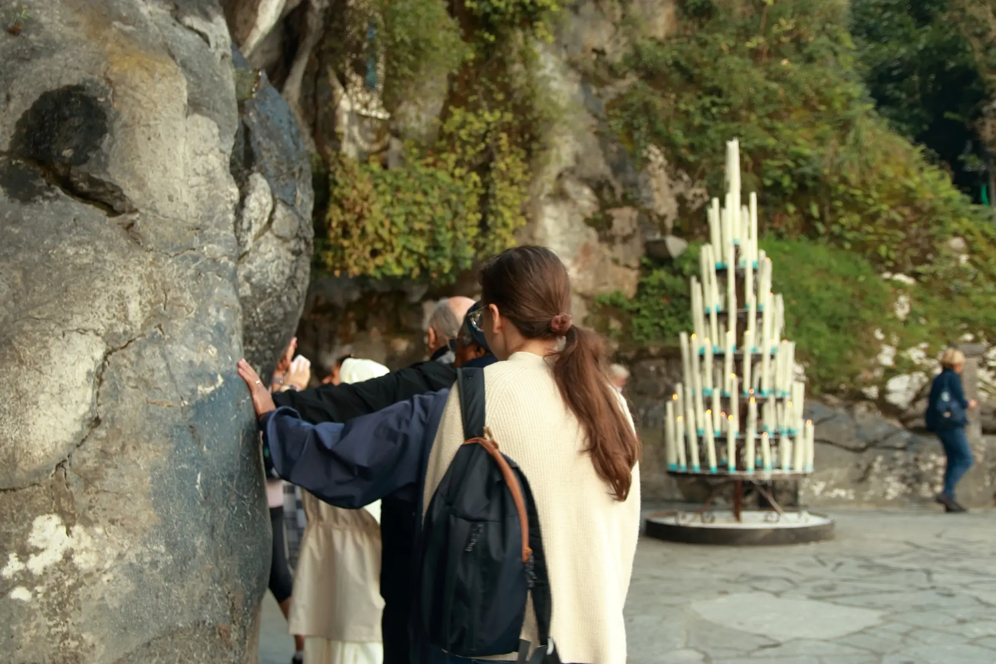 Pellegrini raccolti in preghiera alla Grotta di Lourdes, luogo simbolo del pellegrinaggio mariano. Flyness voli charter per pellegrinaggi.