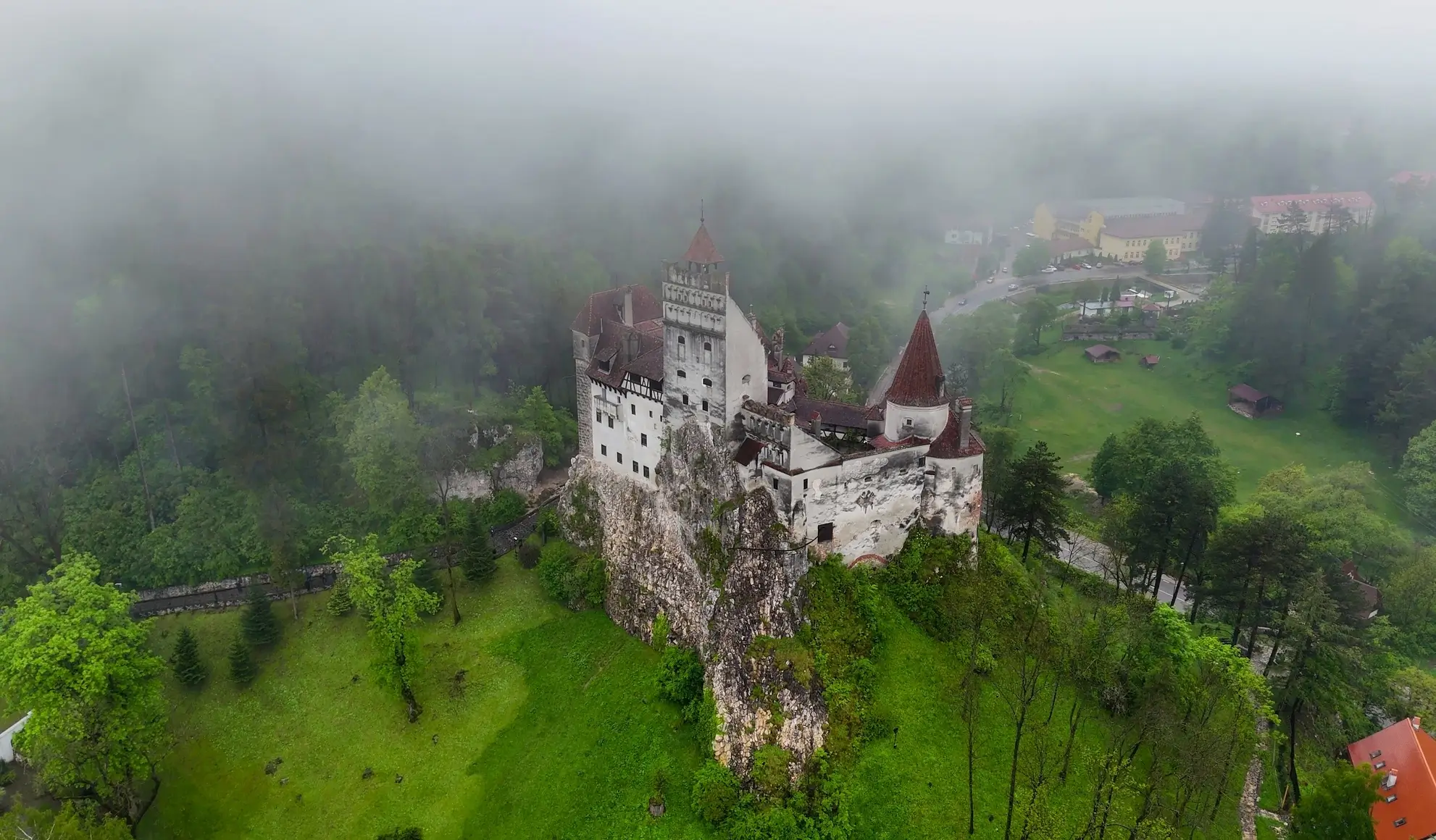 viaggio-incentive-transilvania-castello-bran-volo-charter-flyness Vista aerea del Castello di Bran immerso nella nebbia, simbolo dei viaggi incentive in Transilvania con volo charter Flyness.