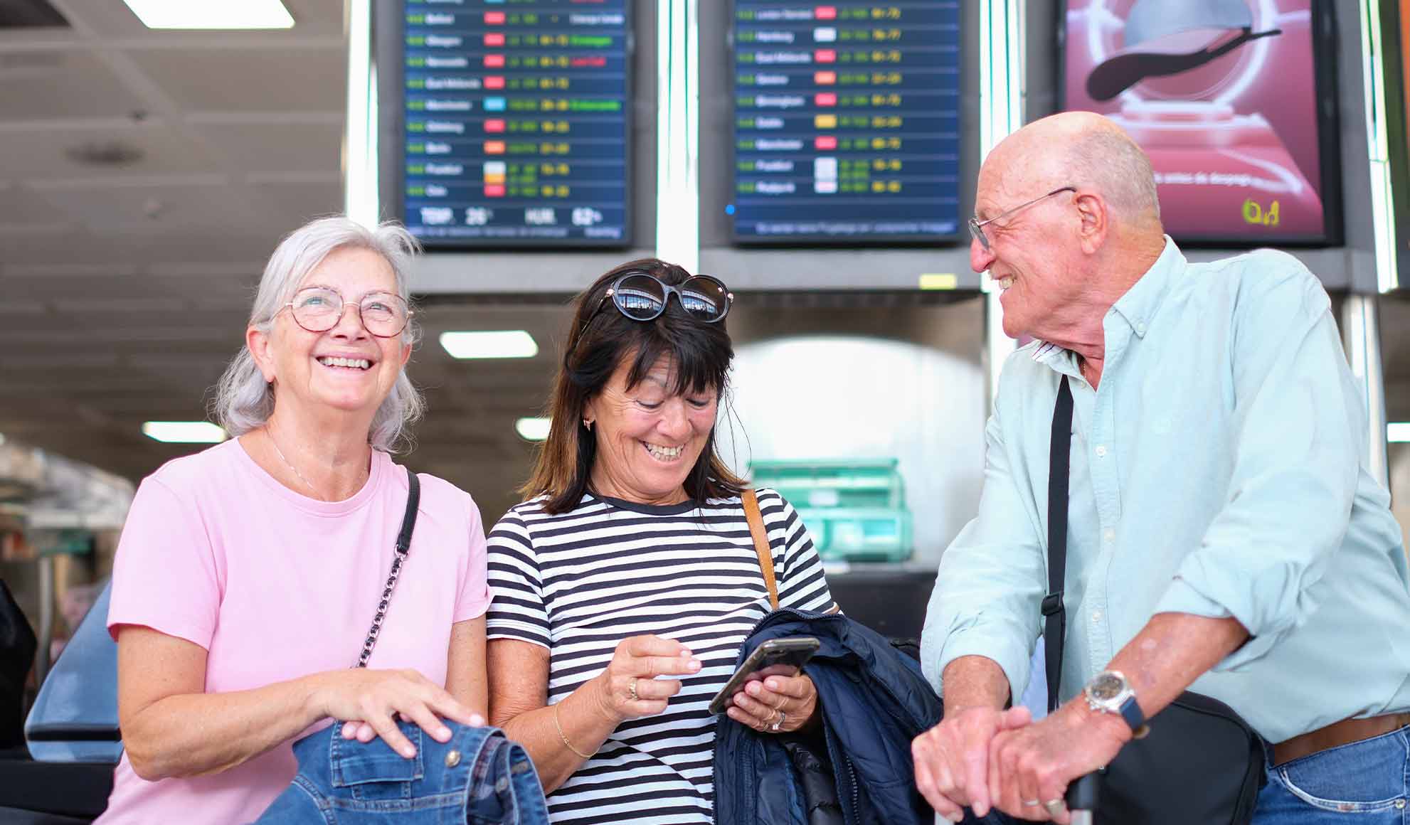 viaggio-spirituale-pellegrinaggio-charter-aereo-flyness Gruppo di pellegrini anziani sorridenti in aeroporto, pronti per un volo charter verso Lourdes, Flyness voli charter per pellegrinaggi.