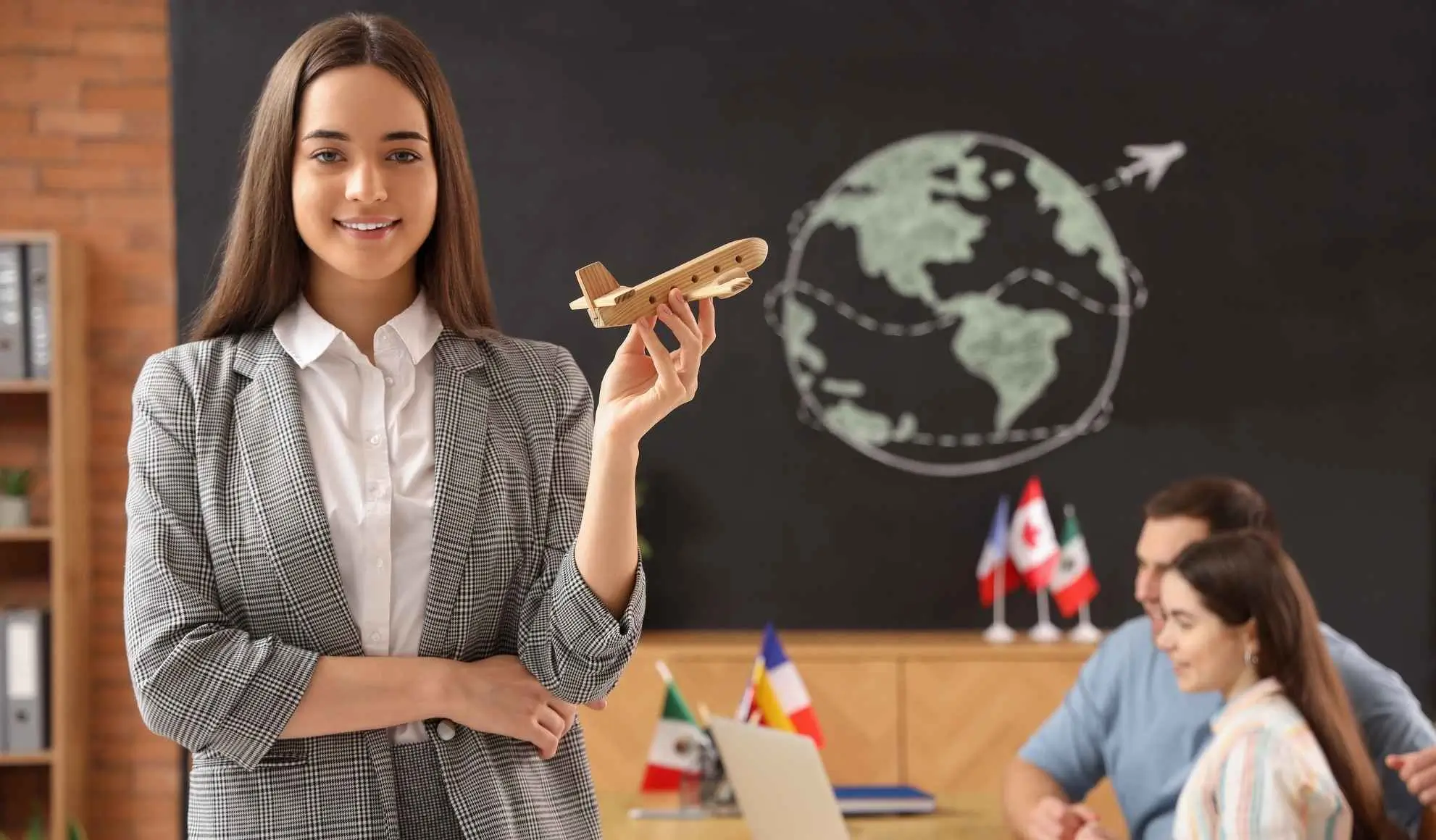 agente-di-viaggio-organizzazione-charter-tifosi Agente di viaggio mostra il modello di aereo mentre pianifica un volo charter per tifosi con due clienti al computer