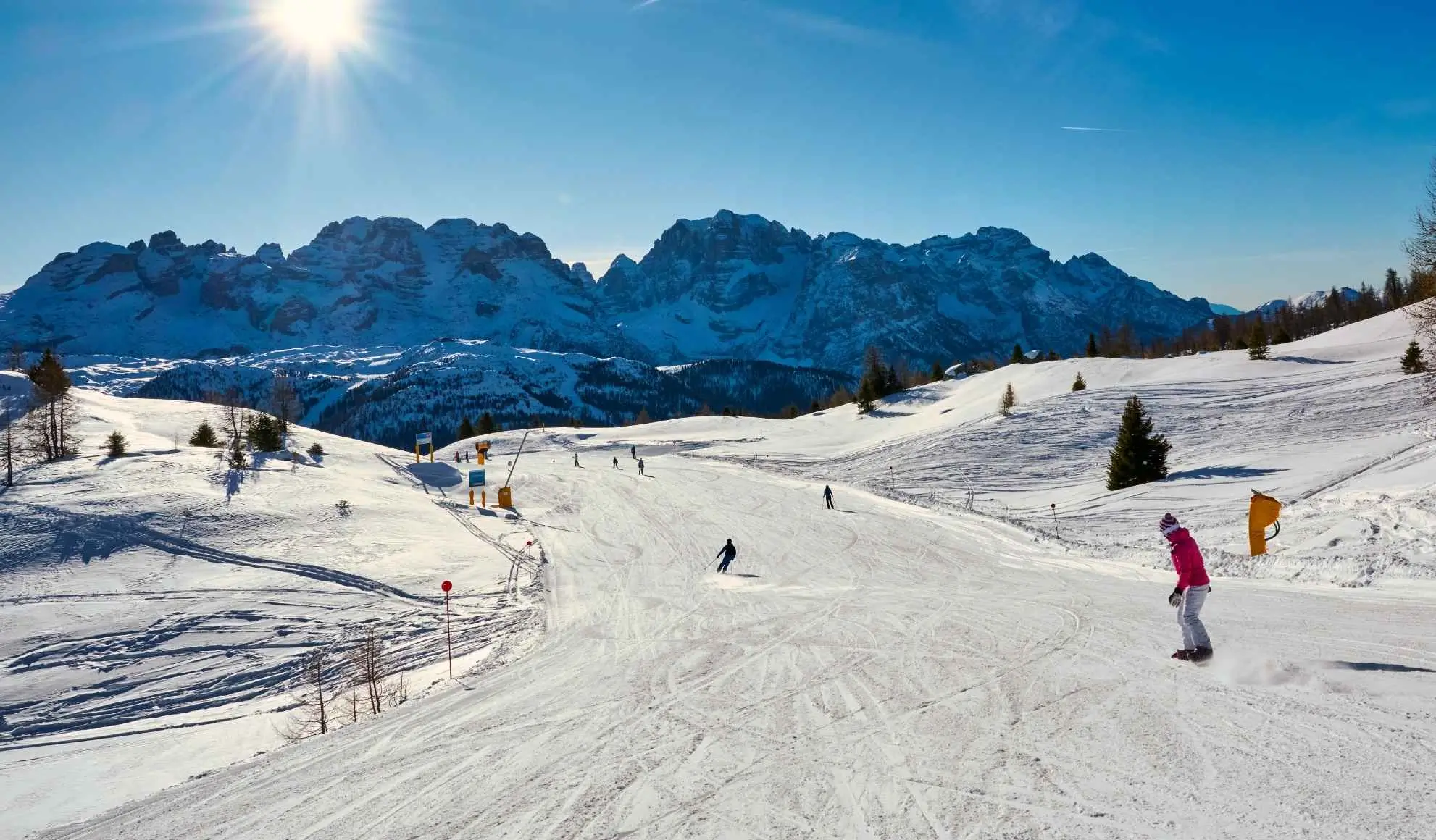 Panorama innevato delle Dolomiti con sciatori, destinazione ideale per la settimana bianca 2025-26 con volo privato Flyness.