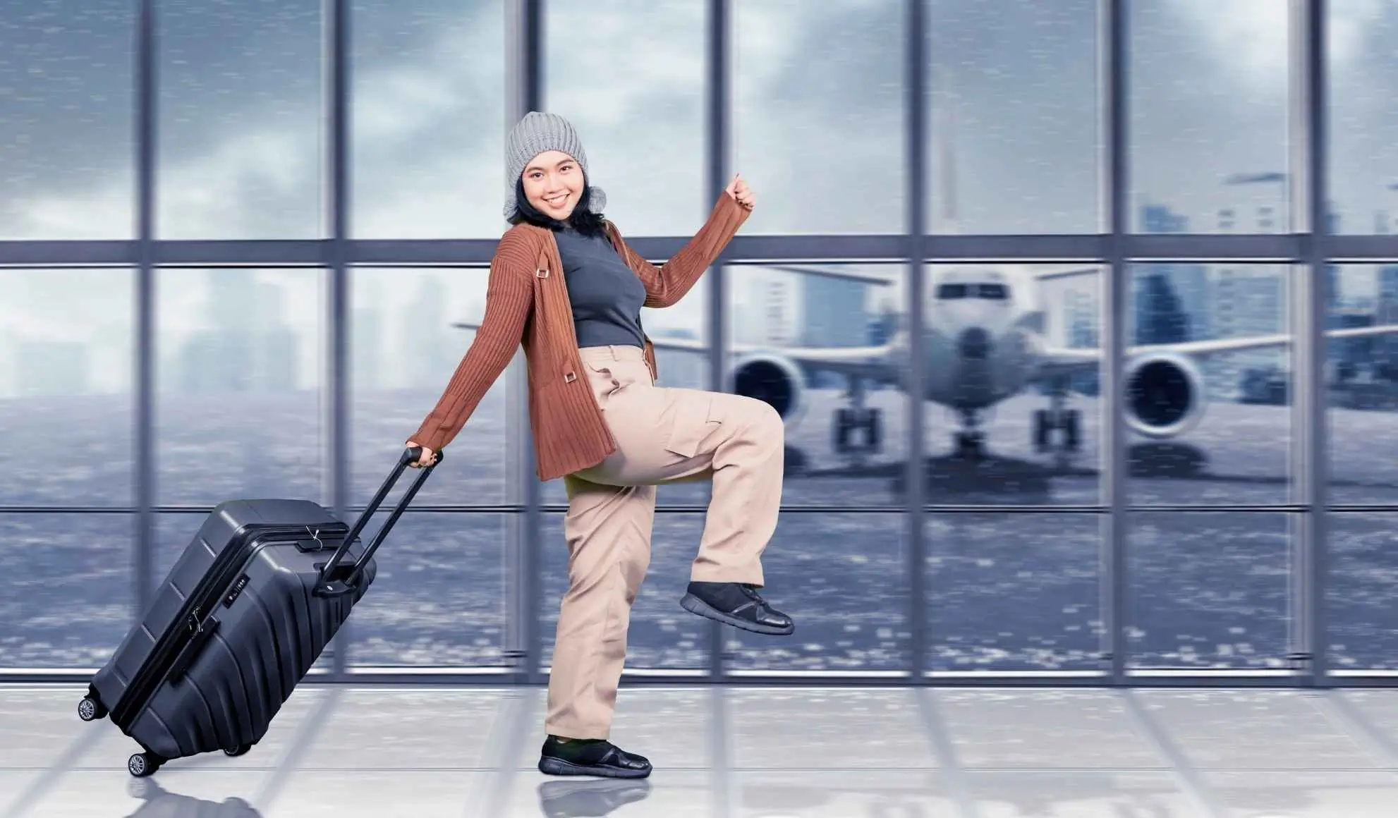 Passeggera sorridente con valigia in aeroporto innevato davanti a un aereo, simbolo dei voli charter Flyness per la settimana bianca.