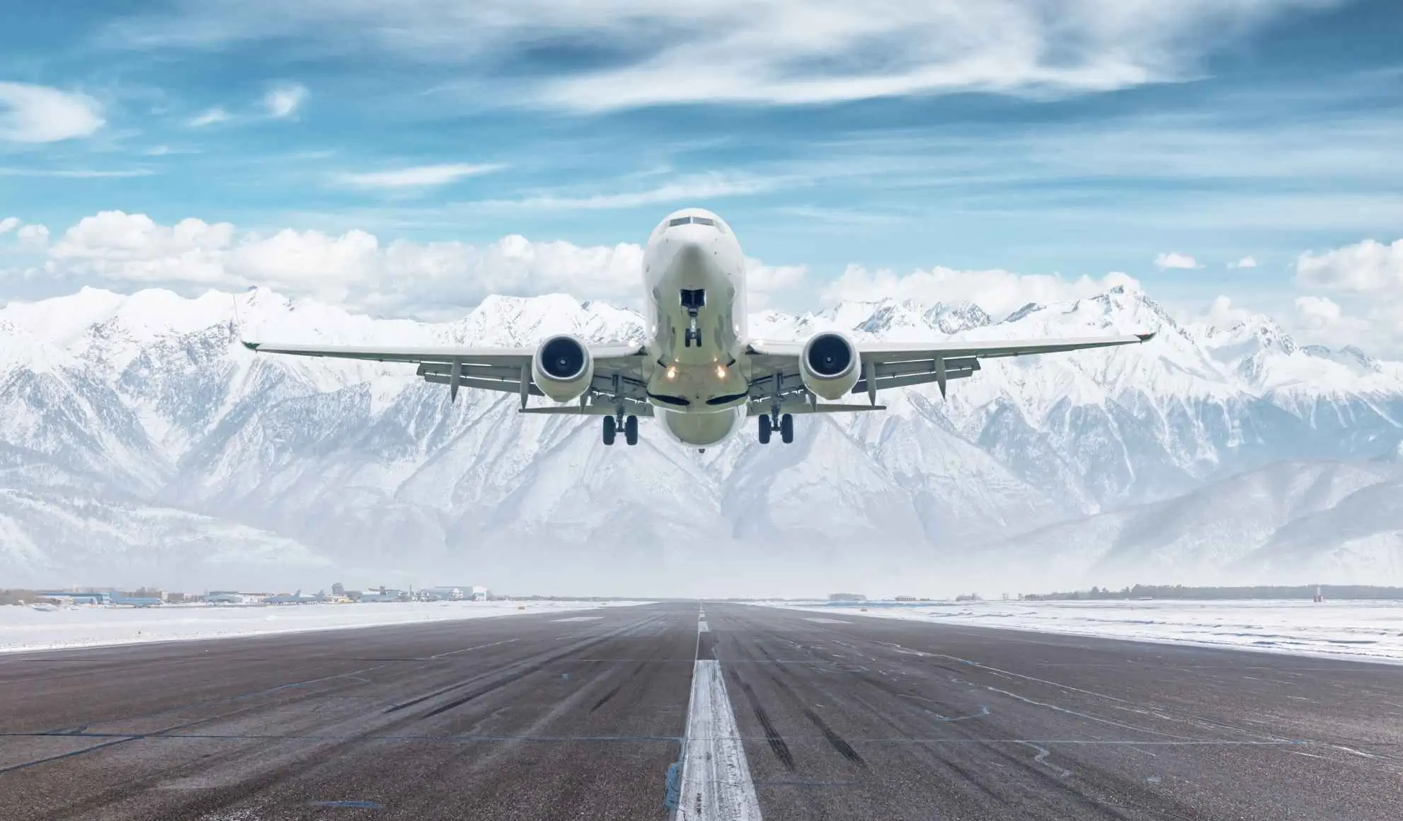 Aereo in decollo con montagne innevate sullo sfondo, simbolo di come la settimana bianca inizi già in volo con Flyness.