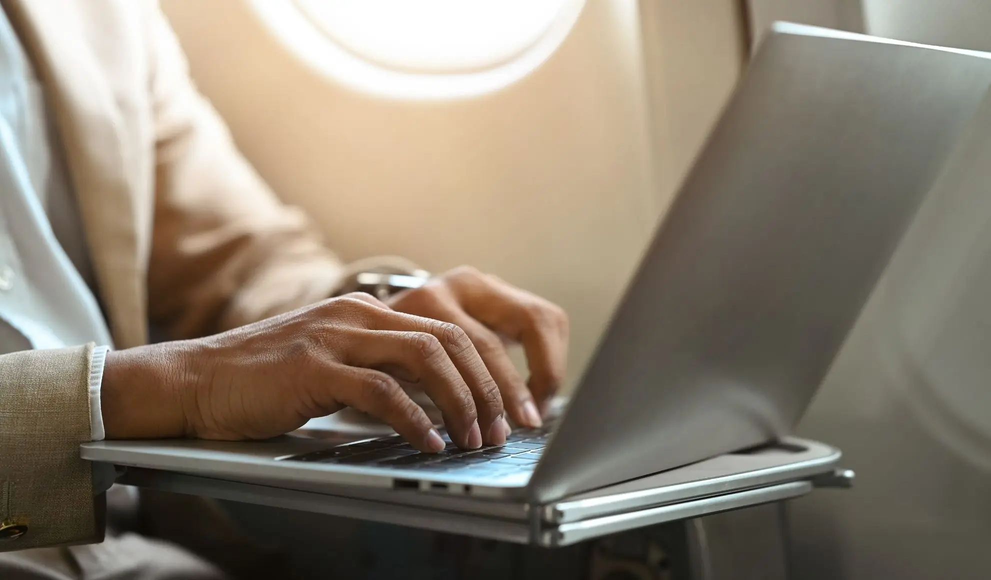 wifi-in-aereo-volo-privato-flyness Manager che lavora al laptop con Wi-Fi in volo e modalità aereo attiva su volo charter