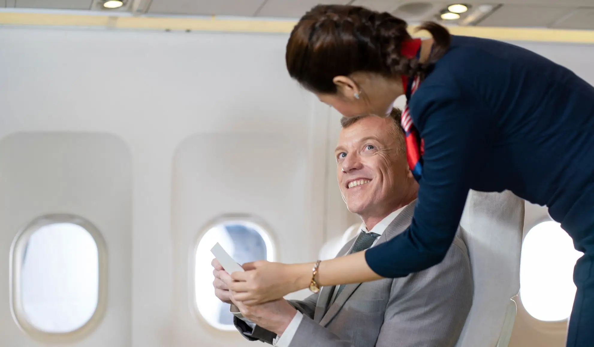 faq-catering-voli-privati-passenger-assistente Passeggero business dialoga con assistente di volo a bordo, simbolo di domande e risposte sul catering nei voli privati