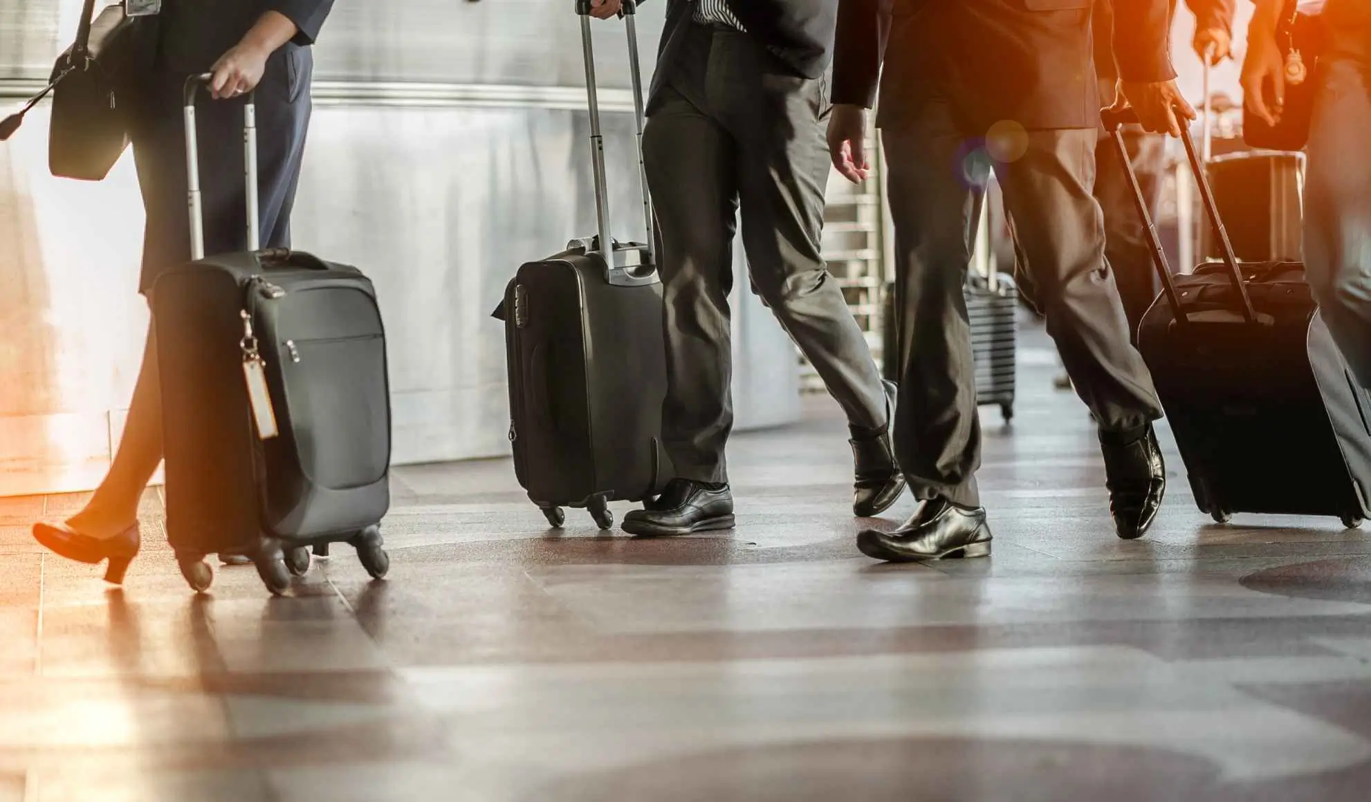 Persone che avanzano in modo coordinato in un terminal aeroportuale con bagagli, durante una partenza organizzata