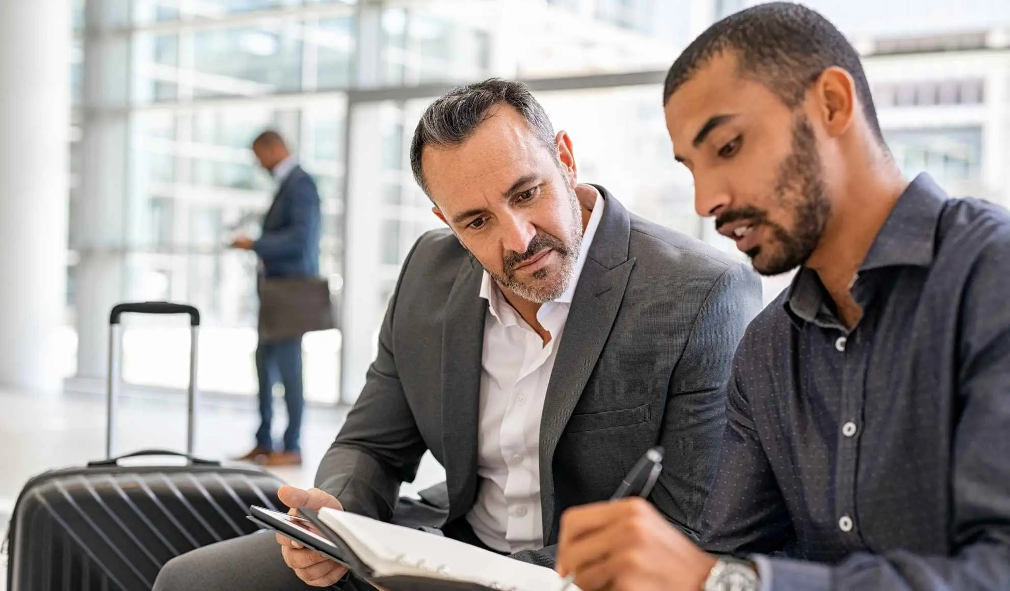 Due professionisti rivedono il piano di una trasferta di squadra in aeroporto consultando documenti.