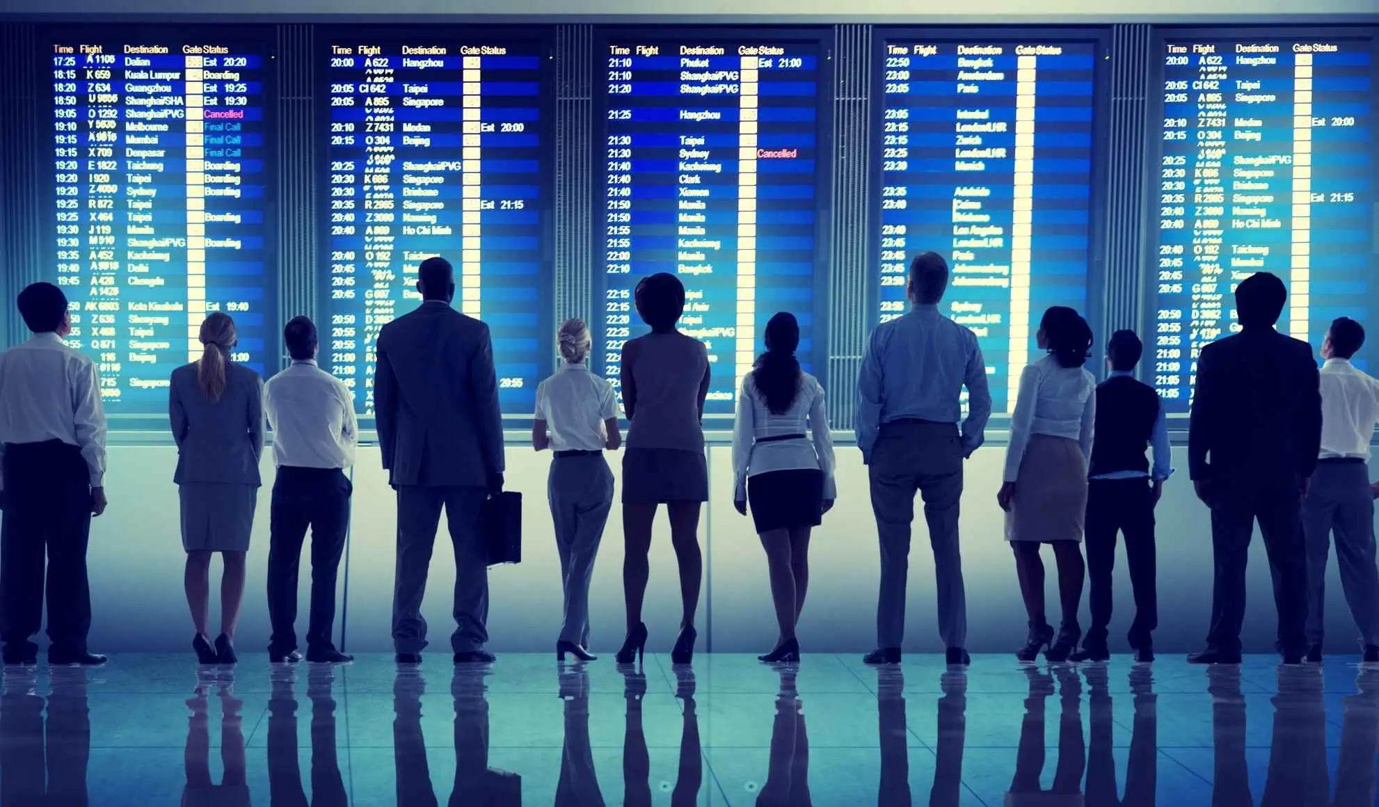 destinazioni-incentive-2026-2027-gruppo-mice-aeroporto Gruppo corporate davanti ai tabelloni delle partenze in aeroporto, simbolo delle destinazioni incentive 2026 e 2027 per eventi MICE.