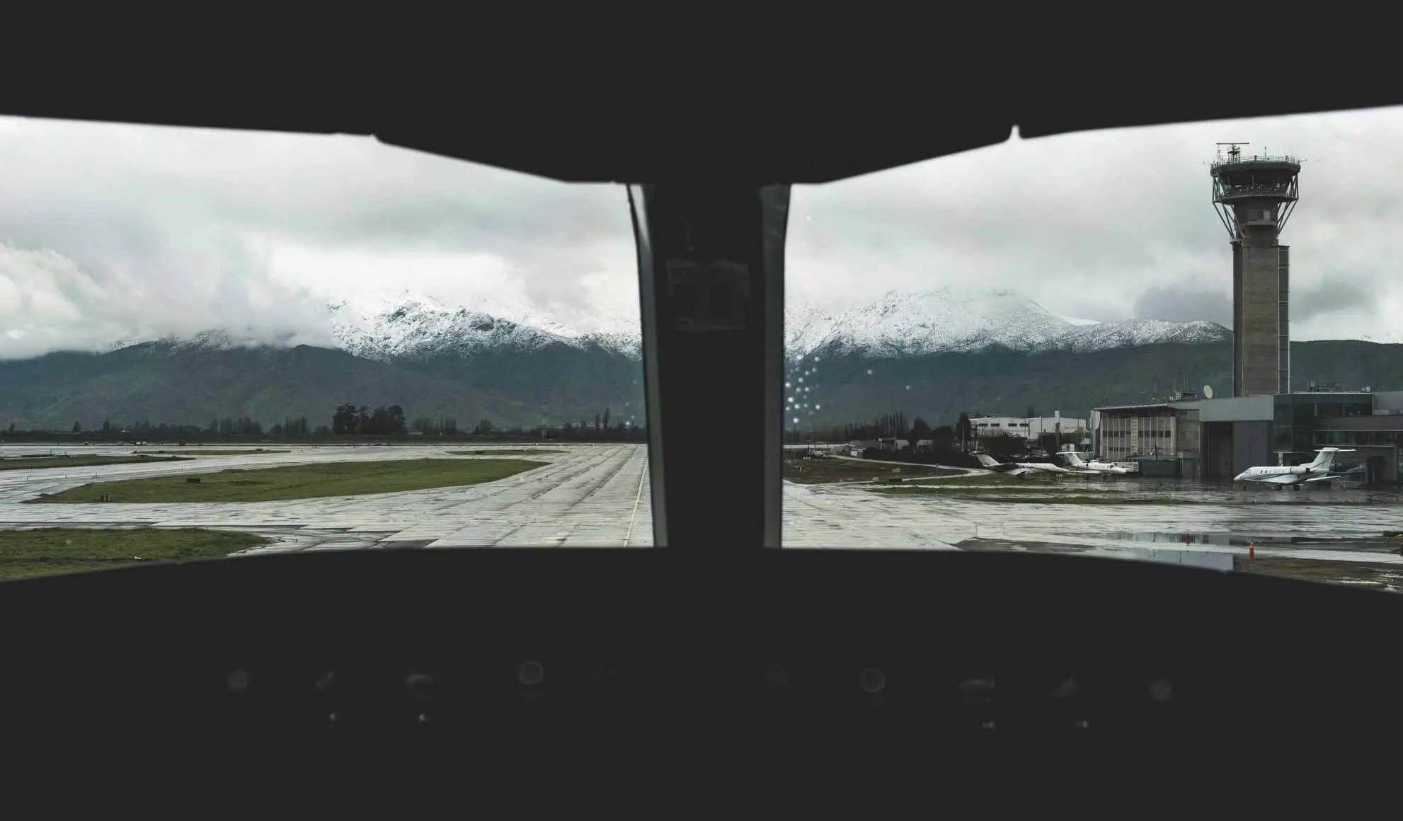 piccolo-aeroporto-vista-cabina-pilota-corto-raggio Pilota in avvicinamento a un piccolo aeroporto, tra pista, torre di controllo e condizioni meteo variabili