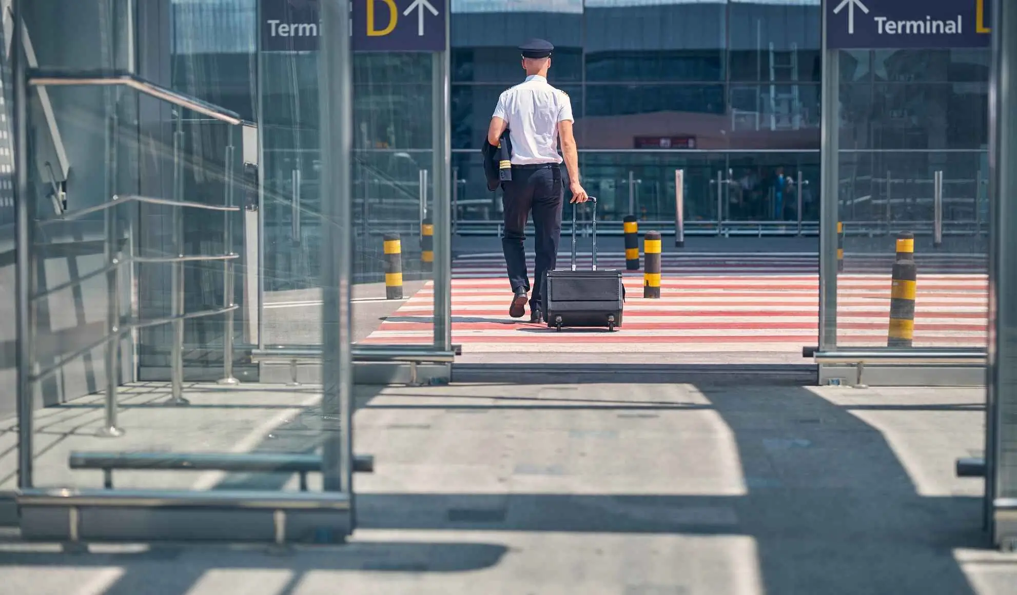 pilota-si-sposta-tra-voli-in-aeroporto Pilota con bagaglio attraversa l’aeroporto tra un volo e l’altro