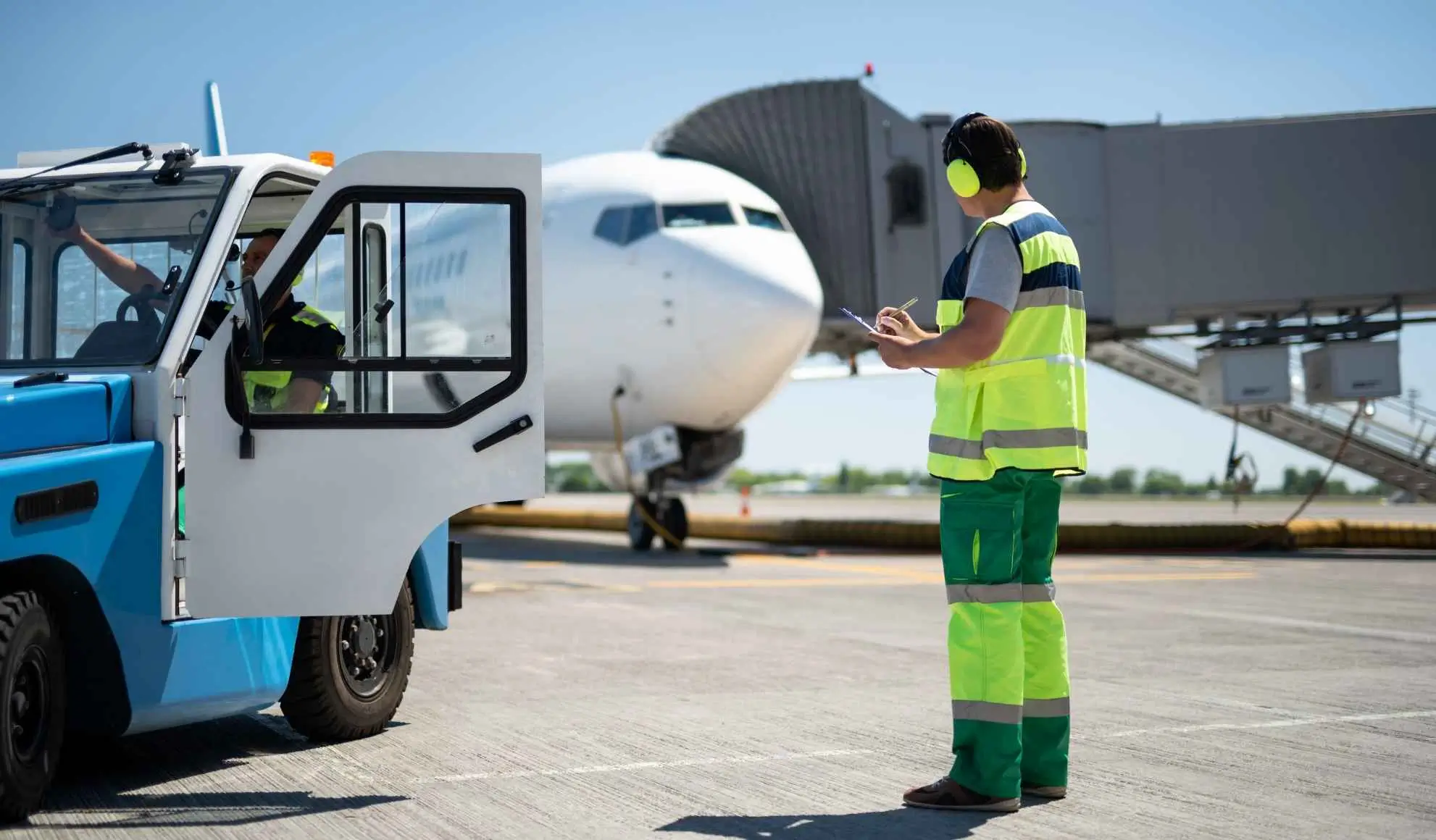 Operatore aeroportuale coordina le attività di handling a terra davanti a un aereo, esempio di operatività nei voli charter Flyness