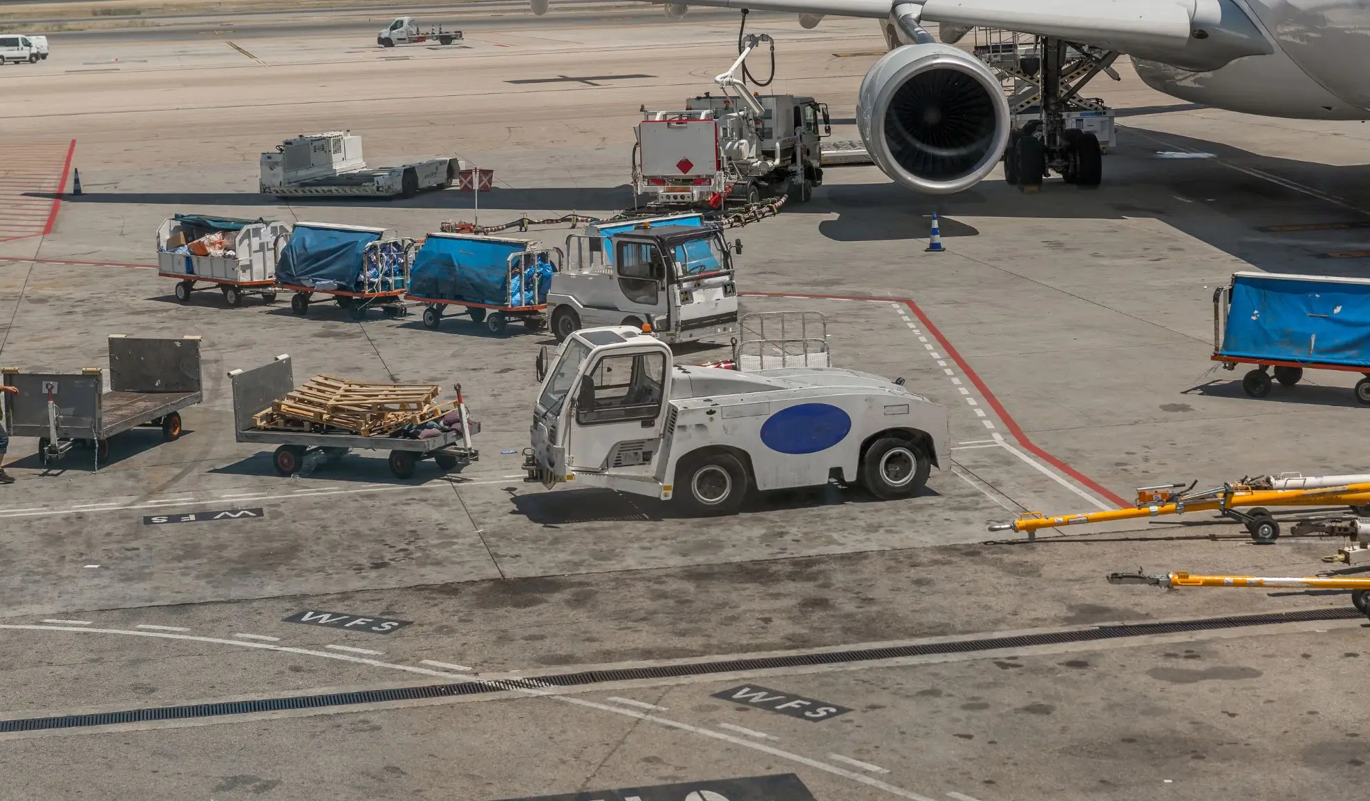 mezzi-handling-aeroportuale-costo-volo-charter Mezzi e attrezzature di handling aeroportuale attorno a un aeromobile durante le operazioni a terra.